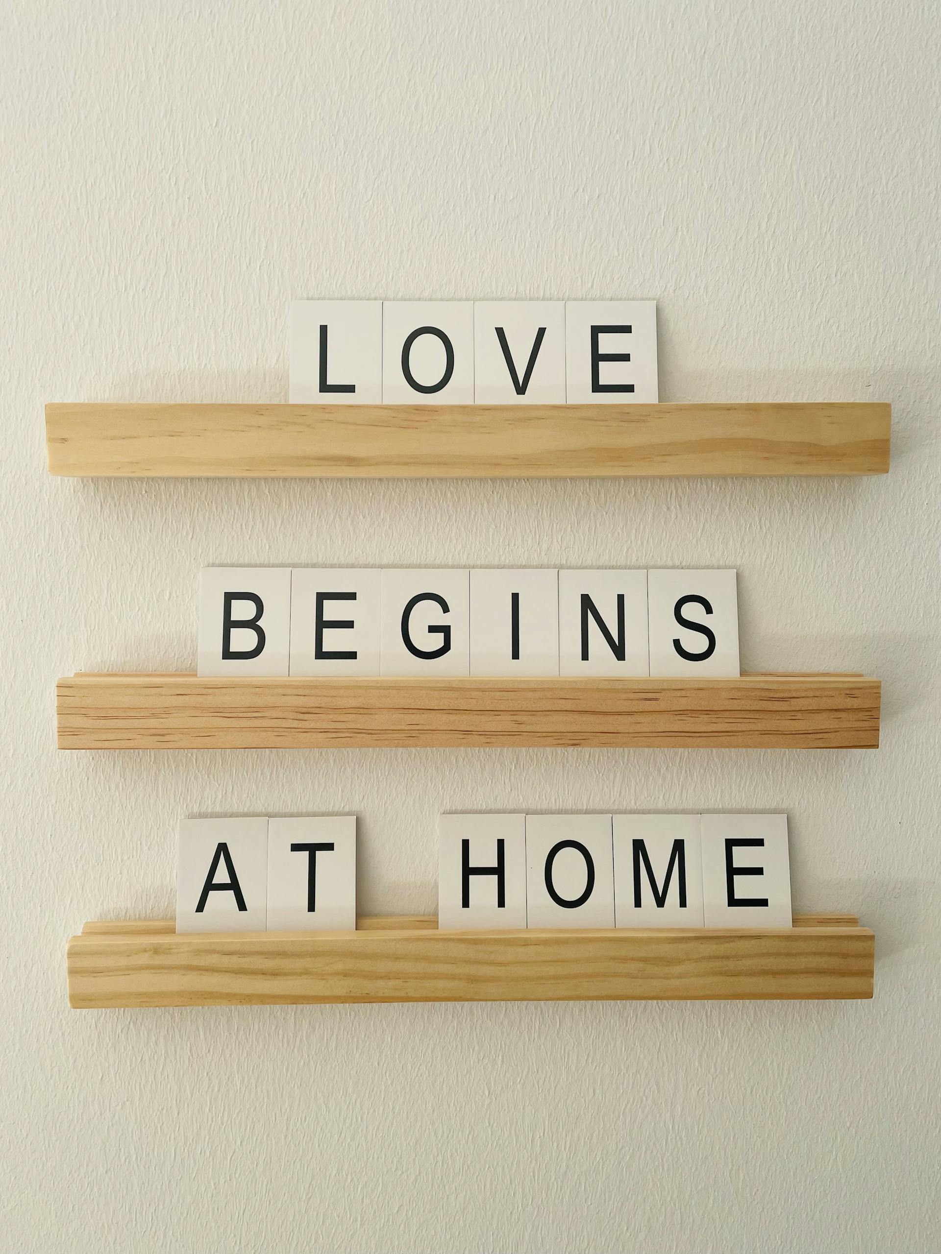 Minimalist wall decor with the message 'Love begins at home' in block letters.